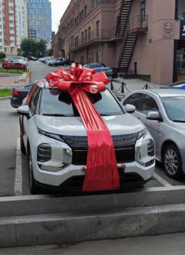 Большой красный  бант на авто Mitsubishi Outlander в новом кузове 2023 в подарок "Раффаэлло"